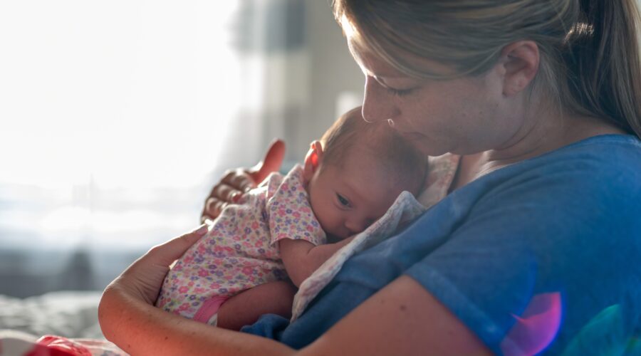 Young woman holding newborn daughter in natural light